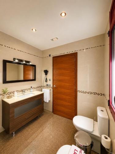 a bathroom with a toilet and a sink and a mirror at Hostal La Tina in Port de la Selva