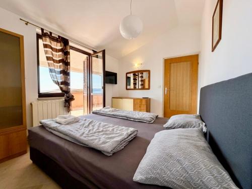 a bedroom with two beds and a large window at Danilo Room in Pula