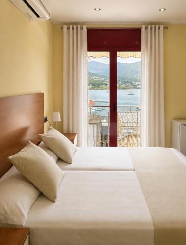 a bedroom with a large bed with a large window at Hostal La Tina in Port de la Selva