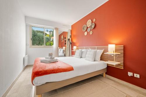 a bedroom with an orange accent wall and a bed at LE MARNI appartement central avec terrasse parking privé in Menton