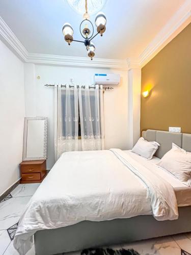 a bedroom with a large white bed and a chandelier at Lita Residence in Yaoundé