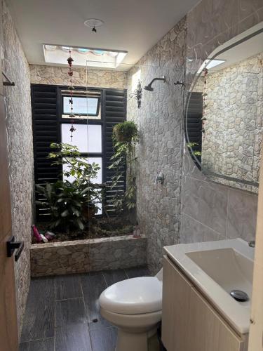 a bathroom with a toilet and a window with plants at Finca San Barbara in Pavas