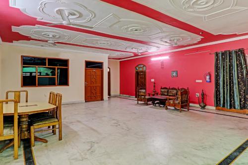 a living room with red walls and a table and chairs at Hotel O Shiva Grand in Chinhat