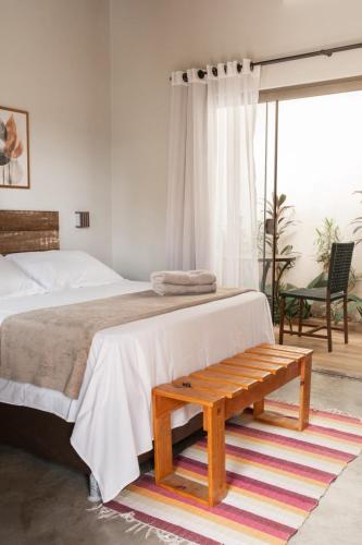 a bedroom with a bed and a wooden bench at Sattva Pousada in Pirenópolis