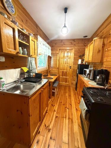 a kitchen with wooden cabinets and a sink and a stove at Letniskowy Domek Paullo in Słajszewo