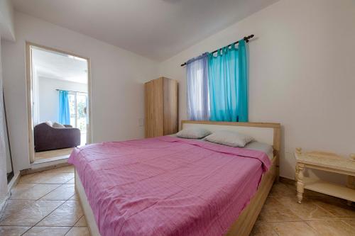 a bedroom with a bed with a pink comforter at FIRST ROW Sea View in Šušanj