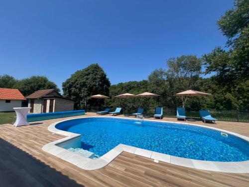 a swimming pool with blue chairs and umbrellas at River House Batrovci in Batrovci