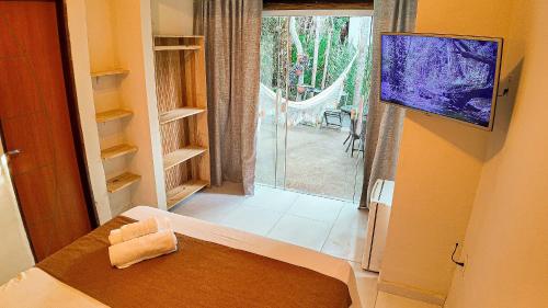 a room with a bed and a tv and a window at Aruana - café da manhã, piscina, na Reserva Sapiranga há 10 min da Vila de Praia do Forte in Castelo da Tôrre