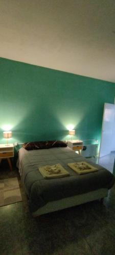 a bedroom with a green wall with a bed and two lamps at Alojamiento DON ANTONIO in Tinogasta
