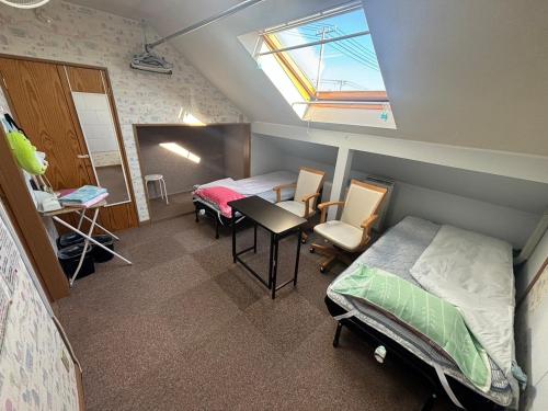 a bedroom with a bed and a desk and a window at Guest House モモ in Obihiro