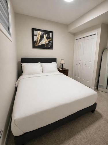 a bedroom with a large white bed in it at Cozy Private 1BR Basement Suite in Calgary