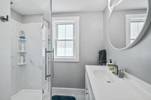 a white bathroom with a sink and a mirror at Willard Modern Cozy Apt 1st Floor in Whitefield