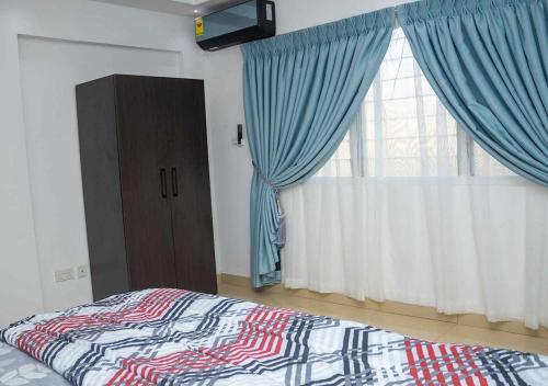 a bedroom with a bed and a window with blue curtains at Mycom Apartment in Kumasi