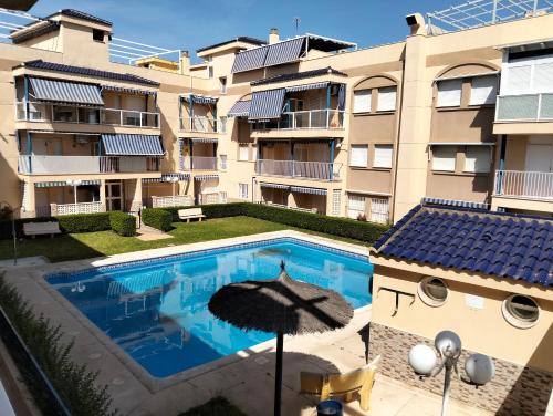 a swimming pool in front of a building with an umbrella at Los Lentiscares Apartment in Torrox Costa