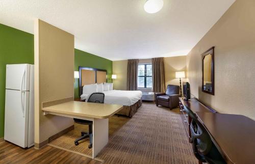 a hotel room with a bed and a desk and a room with a refrigerator at Extended Stay America Select Suites - Appleton - Fox Cities in Appleton