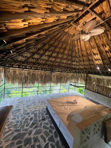 a bed in a thatched room with a ceiling at Finca Campestre Doradal in Doradal