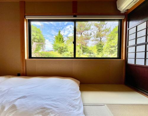 ein Bett in einem Zimmer mit einem großen Fenster in der Unterkunft Room 48 in Takayama