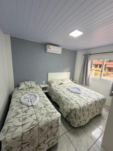 a room with two beds and a window at Aptos Weber - Piratini in Gramado