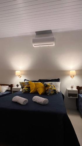 a bedroom with a large bed with yellow pillows at São Gabriel Centro Studios & Suítes in São Gabriel