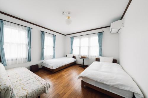a room with two beds and two windows at Lodge Kent & Cottage Kent in Hokuto