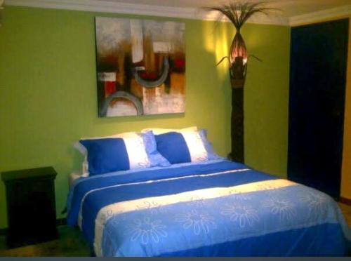 a blue and white bed in a green bedroom at Posada Doña Alcinda in Catia La Mar