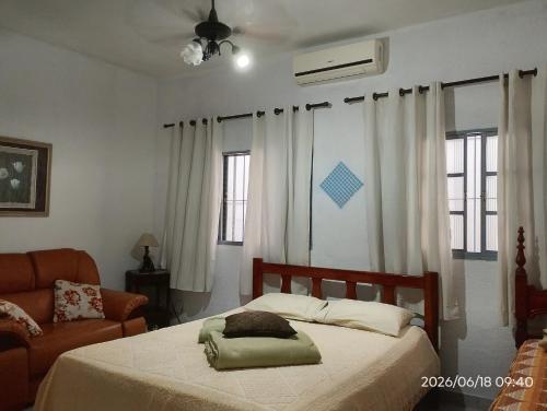 a bedroom with a bed and a chair and windows at CASA com ACOMODAÇÃO para 6 PESSOAS in Guaratinguetá