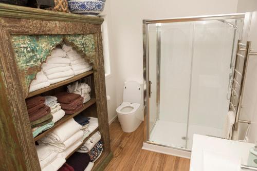 a bathroom with a shower and a toilet and towels at Nyima Tashi Buddhist Centre in Auckland