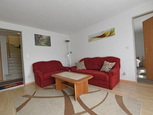 un soggiorno con 2 divani rossi e un tavolo di Modern Apartment in Mastrils near Forest a Mastrils