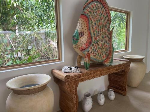 a statue of a peacock sitting on a table next to vases at Ubuntu Villa in Ko Phangan