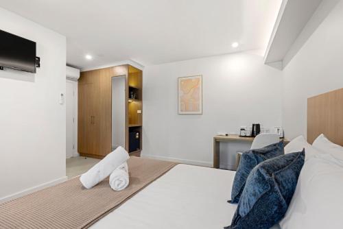 a bedroom with a white bed and a kitchen at Modern Queen Studio - 6 Mins to Callala Beach in Callala Beach