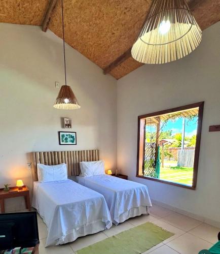 a bedroom with two beds with white sheets and a window at Casa Mangaba da Praia in Prado