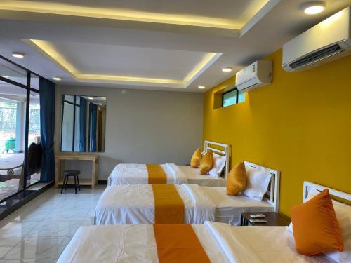a hotel room with two beds and a yellow wall at Kep Orchid Cafe in Phumĭ Dâmnăk Châng'aeur