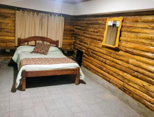 a bedroom with a bed and a wooden wall at Cabañas Espacio Prana in Uspallata