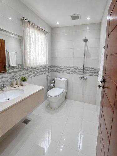 a white bathroom with a toilet and a sink at The Corvane Residence in Islamabad