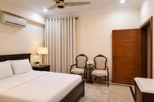 a hotel room with a bed and two chairs at The Corvane Residence in Islamabad