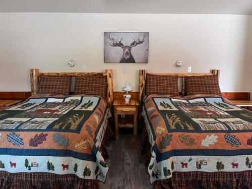 a bedroom with two beds and a picture of a deer at Denali Fireside Cabin & Suites in Talkeetna