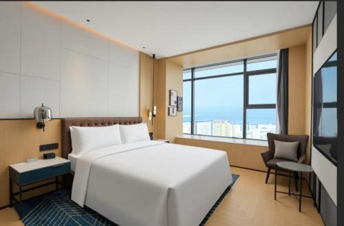 a bedroom with a white bed and a large window at Four Points by Sheraton Rizhao Central Activities Zone in Rizhao