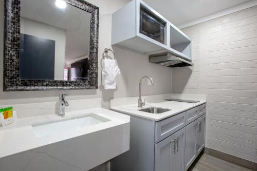 a white bathroom with a sink and a mirror at The Inn On 66 Flagstaff in Flagstaff