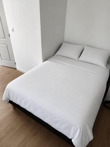a bed with white sheets and pillows in a room at Bleu d'Aubrac Climatisé in Marvejols