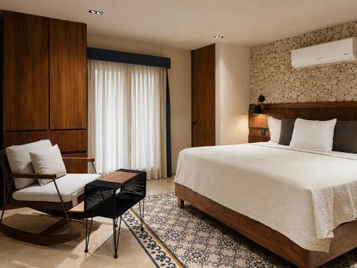 a hotel room with a bed and a chair at Hotel Travertino in Mérida