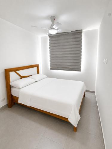 a white bedroom with two beds and a window at Apto Isabelu Girardot in Girardot