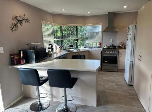 a kitchen with a white counter and two bar stools at Peaceful BnB in Rotorua