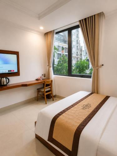 a bedroom with a bed and a desk and a television at Kiwi Beachside Hotel & Cafe Da Nang in Danang