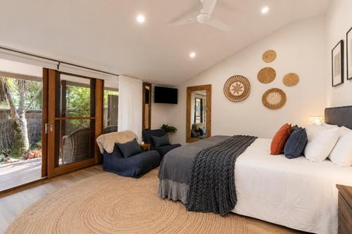 a bedroom with a bed and a chair and a window at Cape Byron Retreat (Adults-Only) in Byron Bay