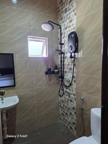 a shower in a bathroom with a toilet and a sink at PJ Luxury Homestay in Sipitang