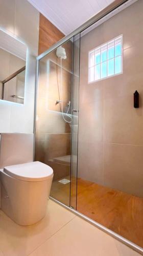 a bathroom with a toilet and a glass shower at São Gabriel Centro Studios & Suítes in São Gabriel