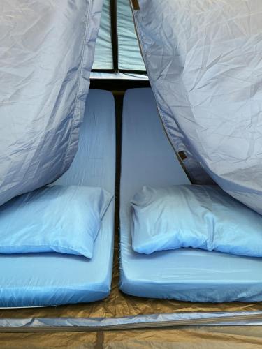 two beds in a tent with two pillows at Redang Campstay in Redang Island