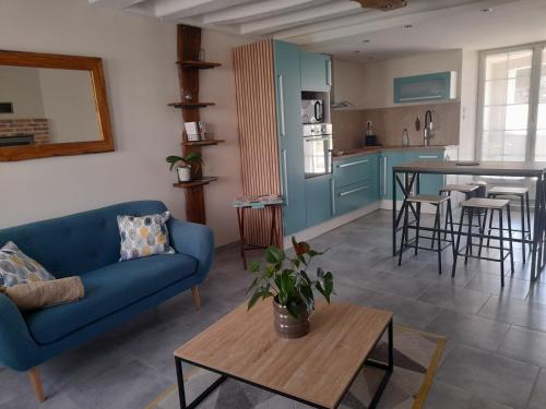 a living room with a blue couch and a table at Le lit de la SEINE in Saint-Seine-lʼAbbaye