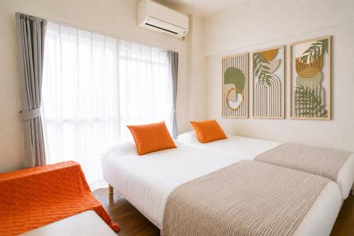 two beds in a room with a window at MinamiFukuokaHouse in Fukuoka