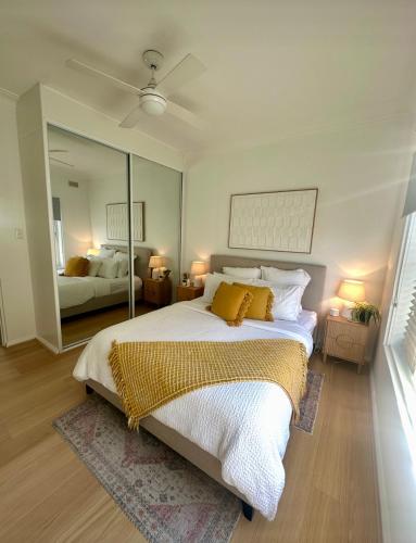 a bedroom with a large bed and a mirror at Cosy and calm unit in Cronulla in Cronulla